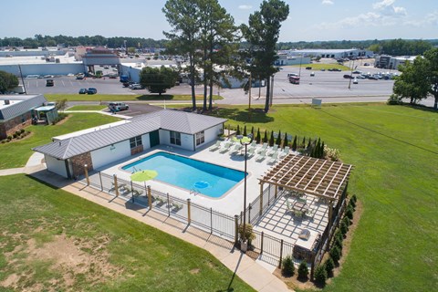 an aerial view of a pool and patio area with a building and a parking lot