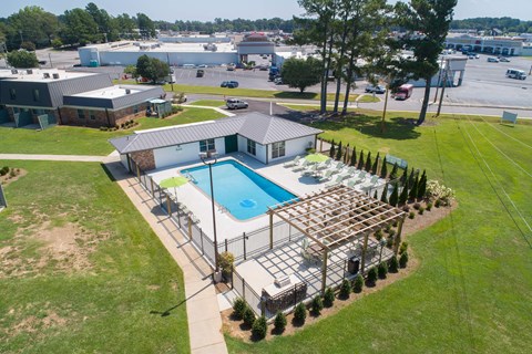 an aerial view of a pool and patio area with a building and a parking lot