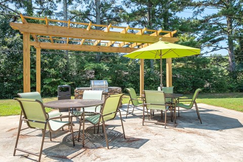 a patio with a table and chairs and a yellow umbrella