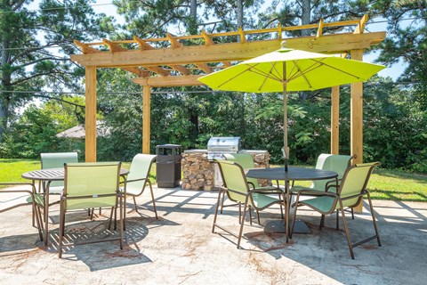 a patio with a table and chairs and a yellow umbrella