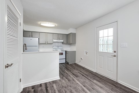 a white kitchen with a white door and a window