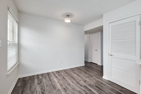 a living room with white walls and wood flooring and a white door