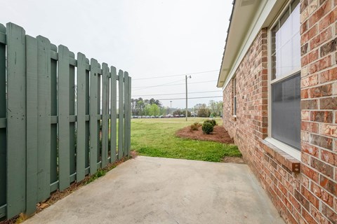 the side of a brick house with a green fence