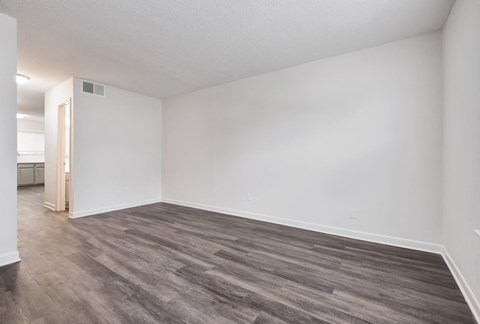 an empty living room with white walls and wood flooring