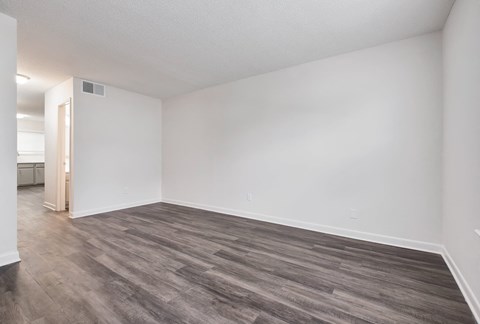 an empty living room with white walls and wood flooring