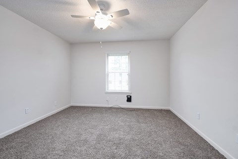 an empty room with a ceiling fan and a window