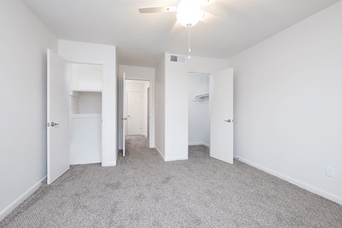 an empty bedroom with white walls and carpet and white closets