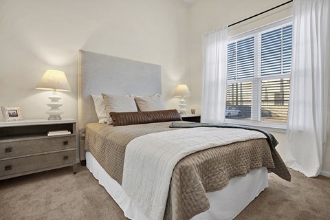 A Model Bedroom with a large bed and two lamps on either side of the bed displaying the size of the bedroom and the height of the ceiling.