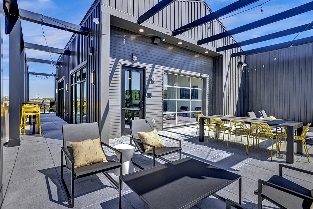 rooftop balcony with chairs and a table and a view of the city at Artisan Flats Apartments in Birmingham, AL