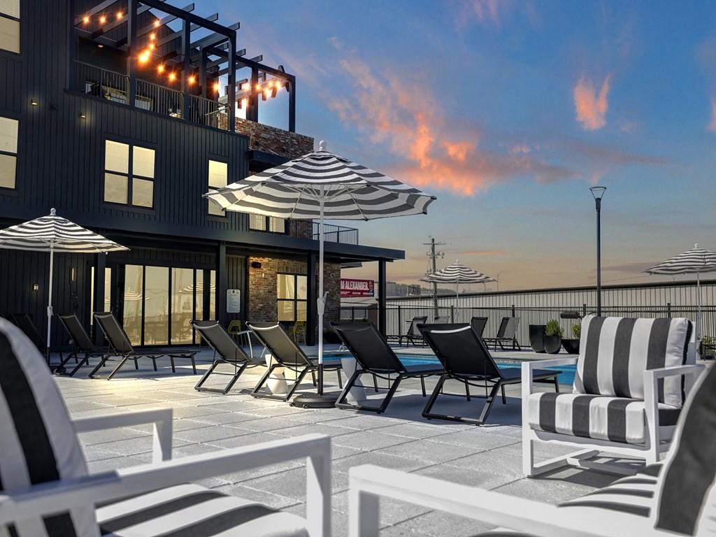 Pool Deck and Seating with Umbrellas at Artisan Flats Apartments in Birmingham, AL an outdoor patio with chairs and umbrellas at dusk at Artisan Flats in Birmingham, AL