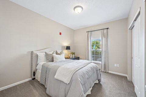 A bedroom with a large bed and a window with curtains.