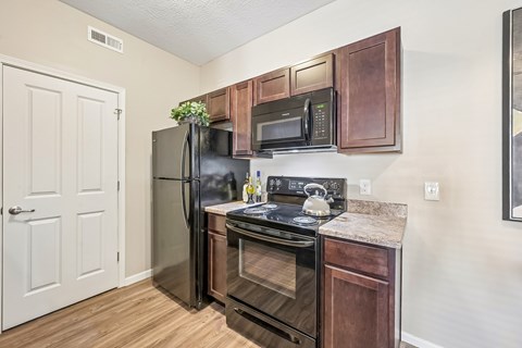 A kitchen with a refrigerator, oven, and microwave.