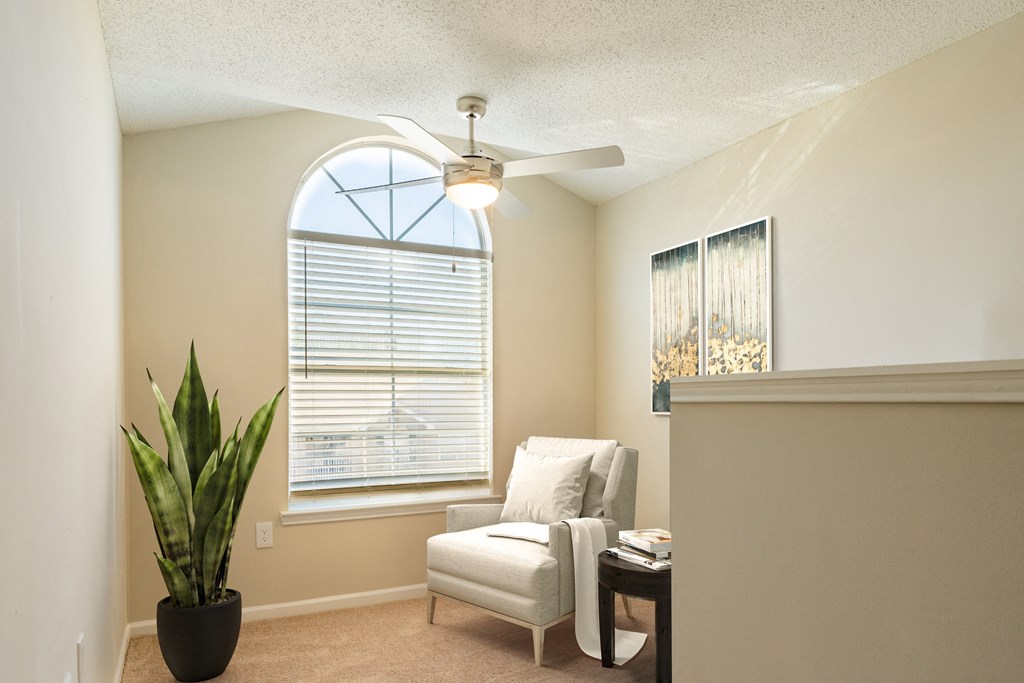 a living room with a ceiling fan and a chair