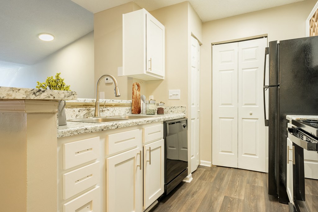 a kitchen with white cabinets and stainless steel appliances and a black refrigerator