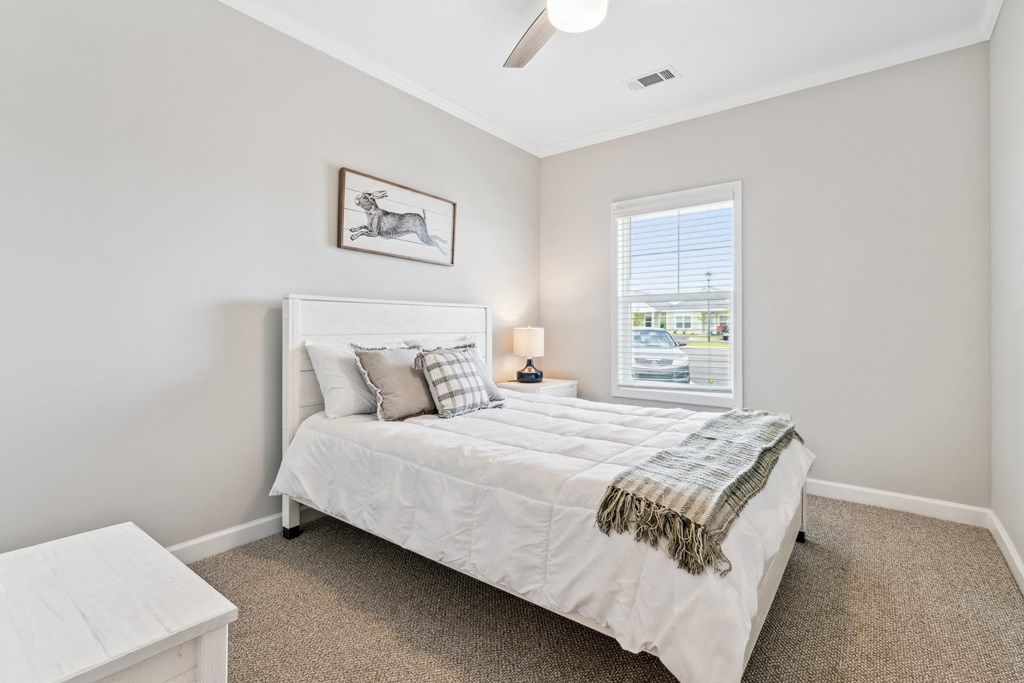 a white bedroom with a white bed and a window