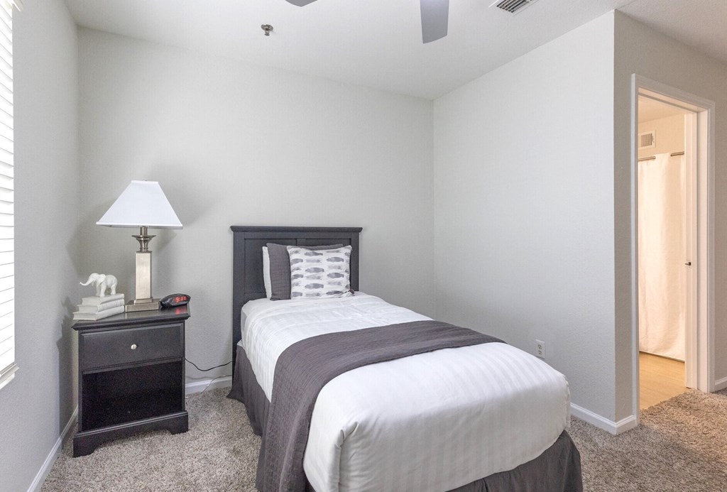 a bedroom with a bed and a nightstand and a mirror