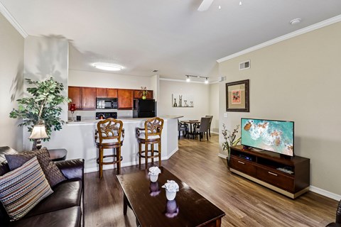 A living room with a brown leather couch, a wooden coffee table, and a television on a wooden stand.
