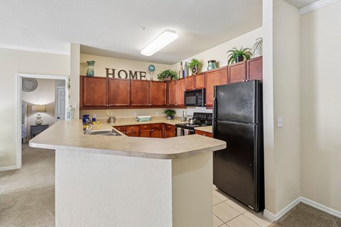 A kitchen with a refrigerator, microwave, and a counter with a sink.