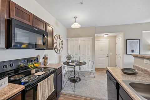 A kitchen with a black stove top oven and a black microwave above it.