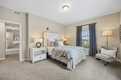 A bedroom with a large bed and a chair.