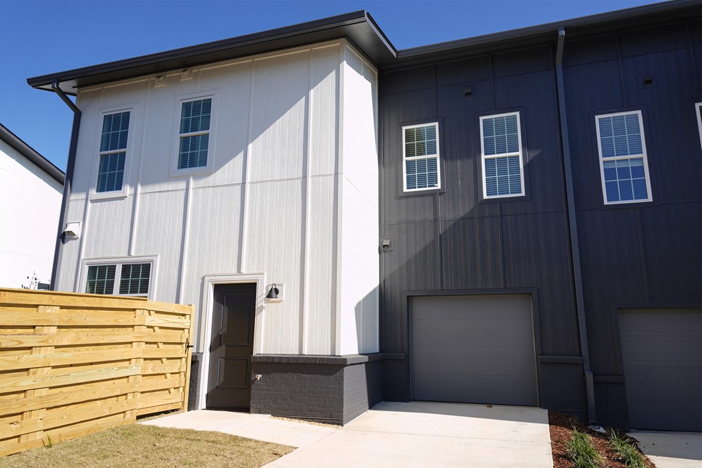 Townhouse building exterior with attached garage and fenced pet yard at West Row Lofts and Townhomes in Birmingham, AL