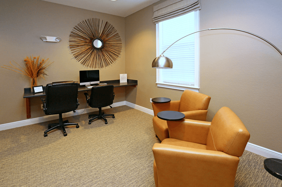 an office with a desk and chairs and a window