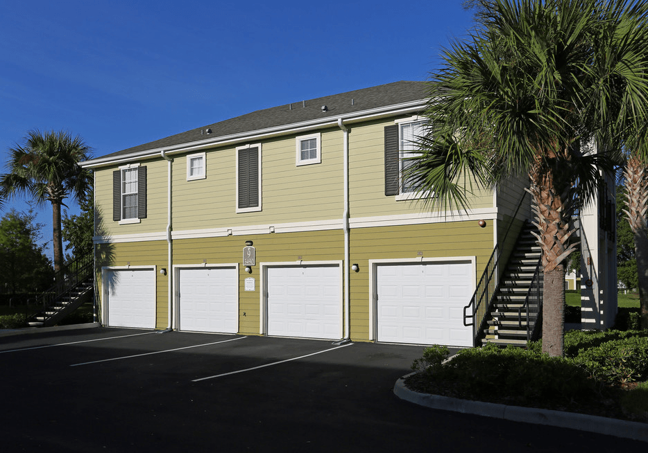 a large yellow house with two garage doors and palm trees