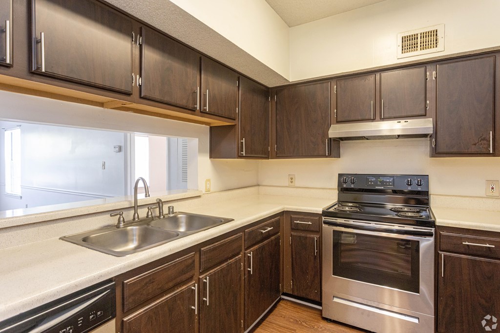 A kitchen with a stove, sink, and cabinets.