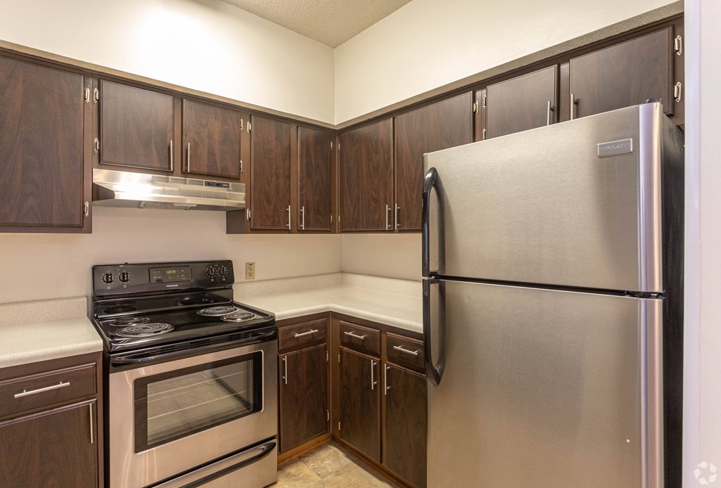 A kitchen with a stainless steel refrigerator, oven, and cabinets.