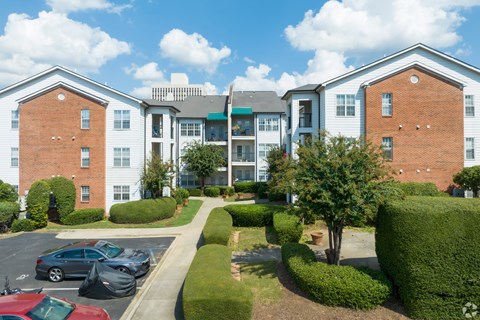 A large apartment complex with a parking lot in front.