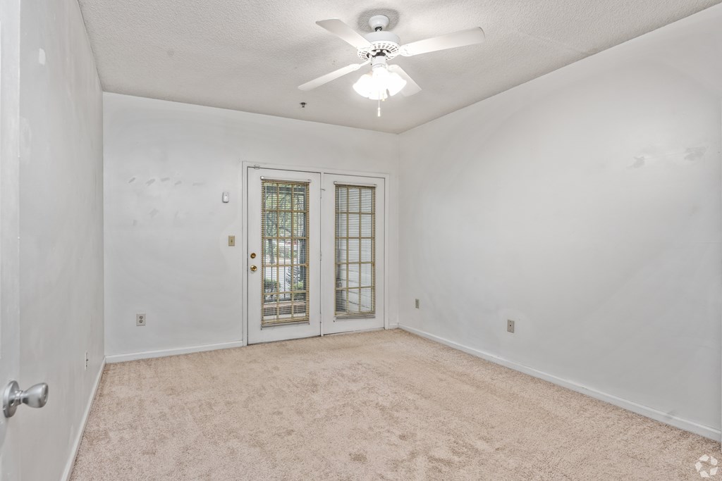 A room with a ceiling fan and a door with a window.