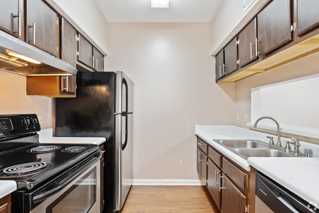 A kitchen with a black refrigerator, stove, and wooden cabinets.