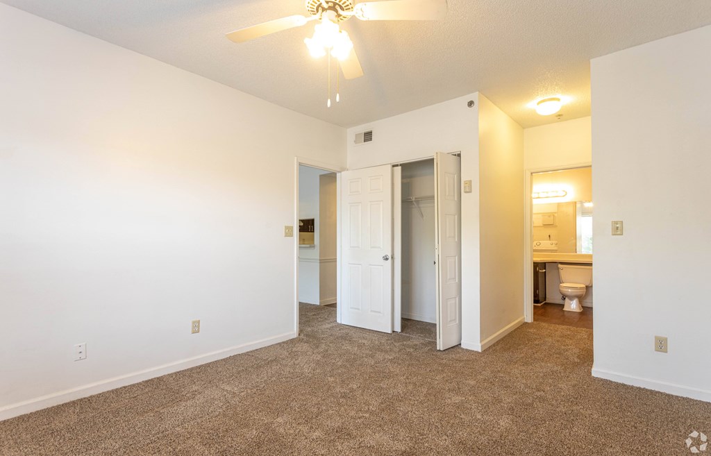 A room with a ceiling fan and carpeted floor.