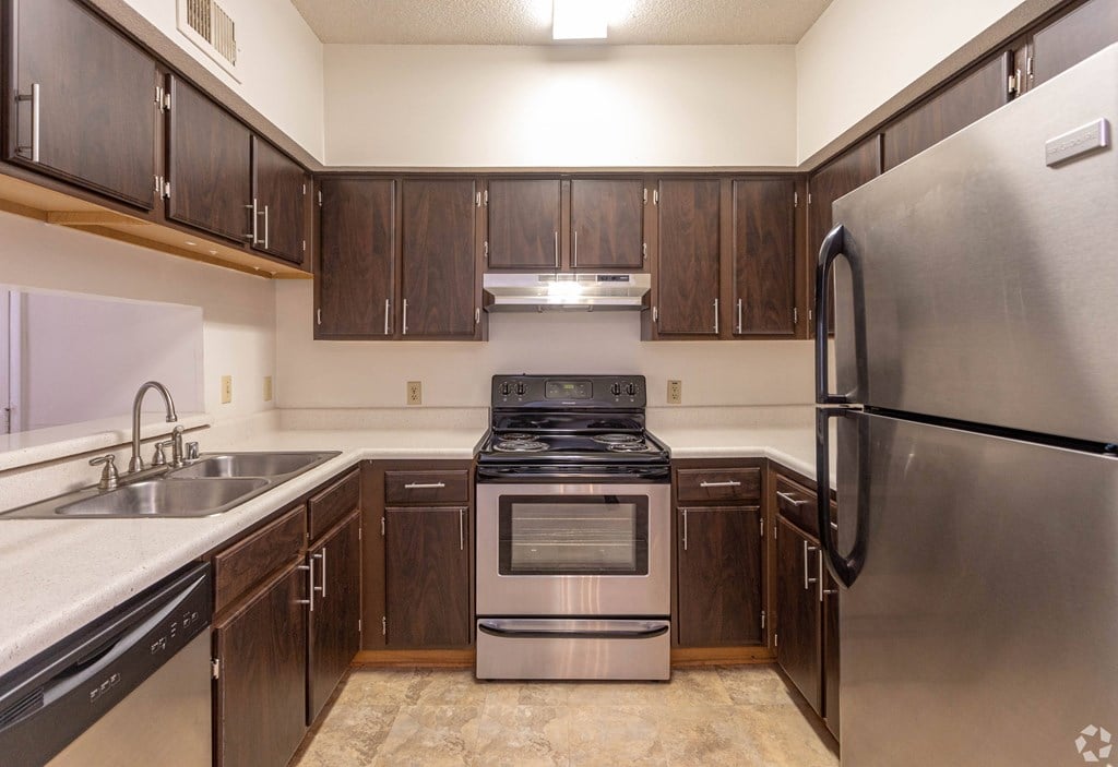 A kitchen with a stainless steel refrigerator, sink, and stove.