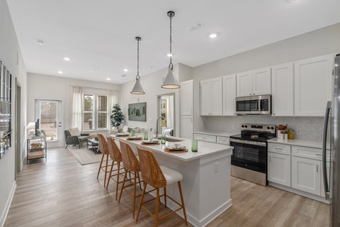 A kitchen with a white counter and wooden chairs.