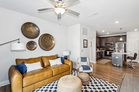 A living room with a brown leather couch and a black and white checkered rug.