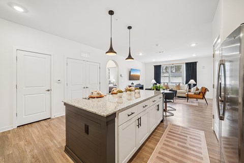 A kitchen with a large island and a refrigerator on the right.