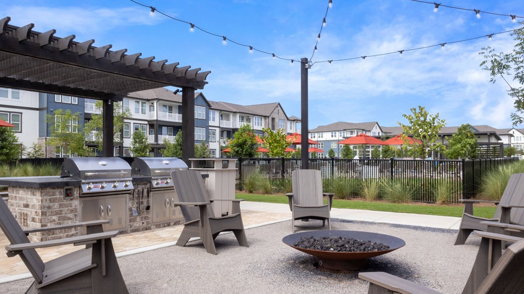 A patio with a fire pit and chairs.
