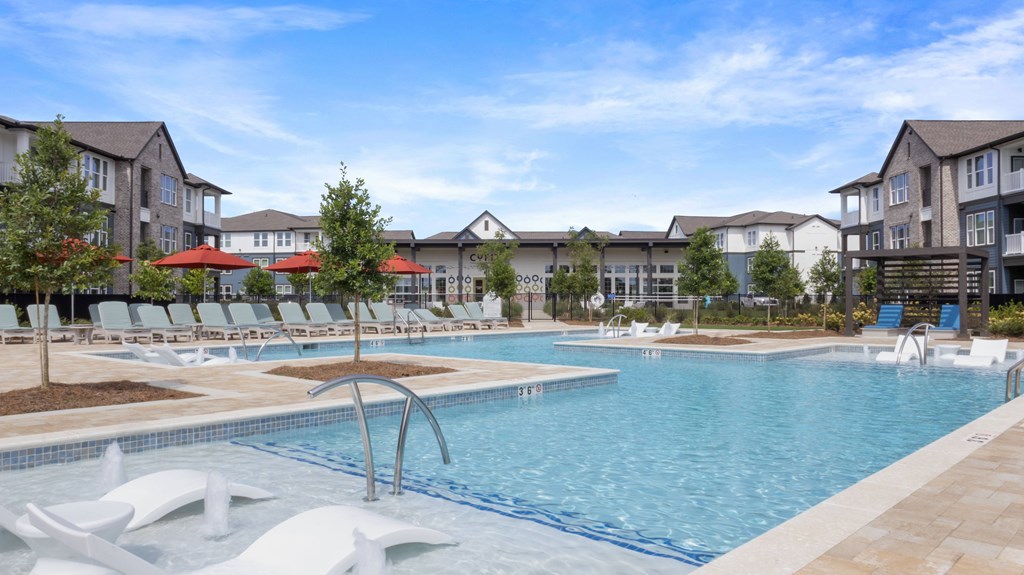 A swimming pool surrounded by white lounge chairs and umbrellas.