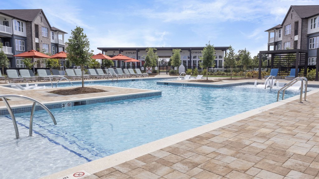 A large outdoor swimming pool with a tiled edge and a few sun loungers.