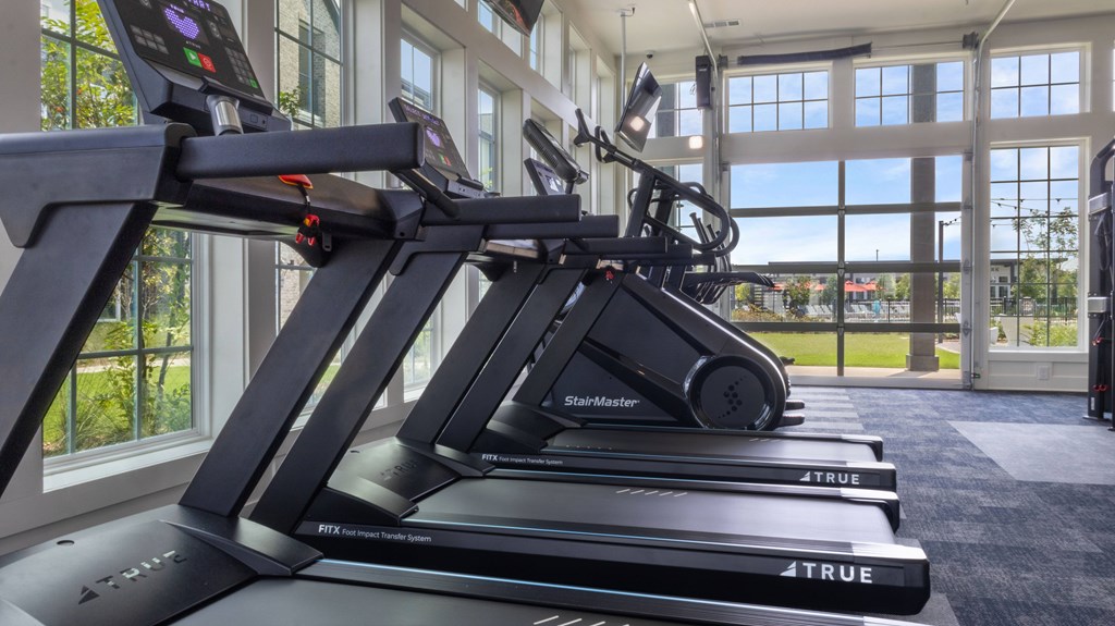 A row of treadmills from the brand 4 TRUE are lined up in a gym.