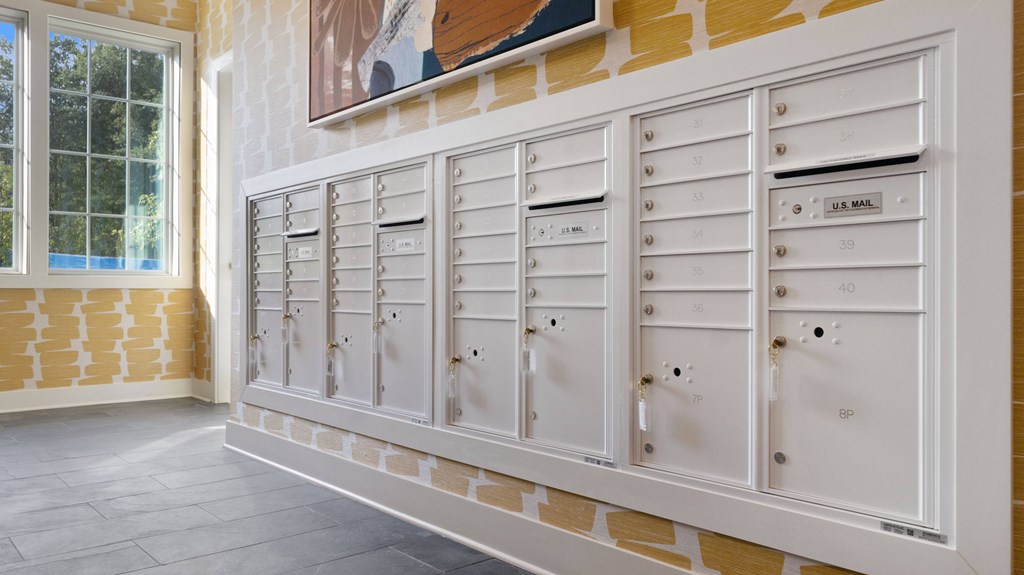 A row of white mailboxes are mounted on a wall.
