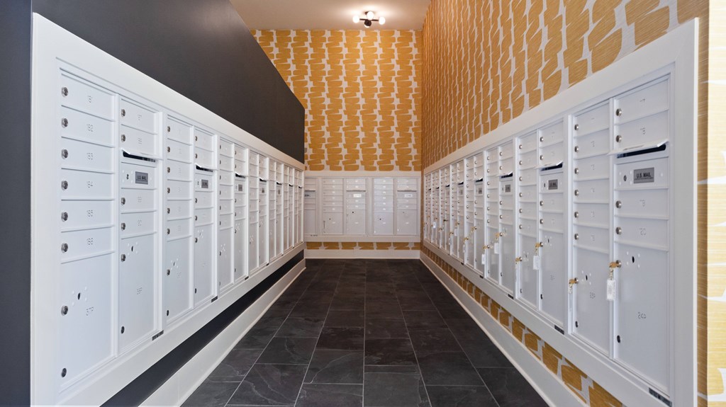 A hallway with a black floor and white walls with a gold patterned ceiling.