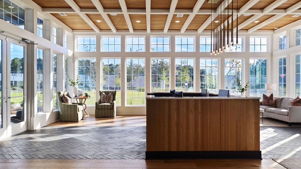 A reception area with a wooden counter and a view of the outdoors through the windows.