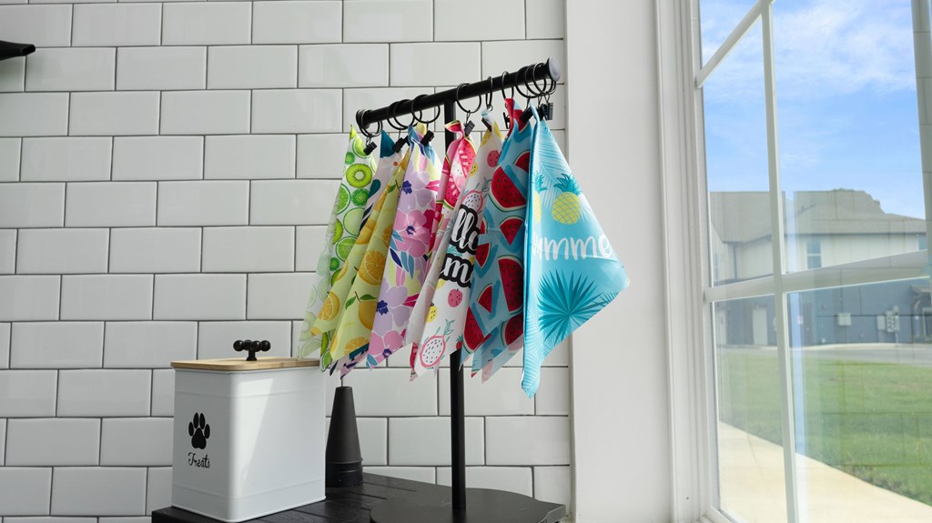 A white dog house is on a black table next to a white brick wall.