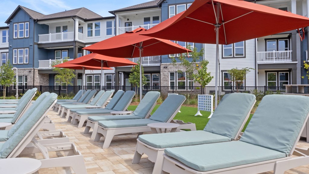 A row of blue lounge chairs are arranged in front of apartment buildings.