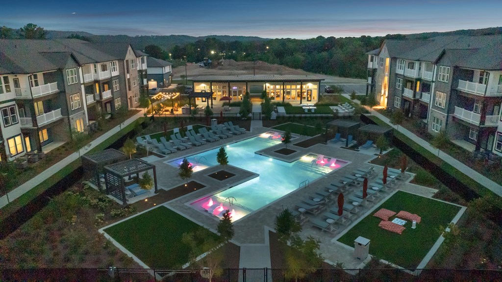 A beautifully lit outdoor pool area at dusk in a residential complex.