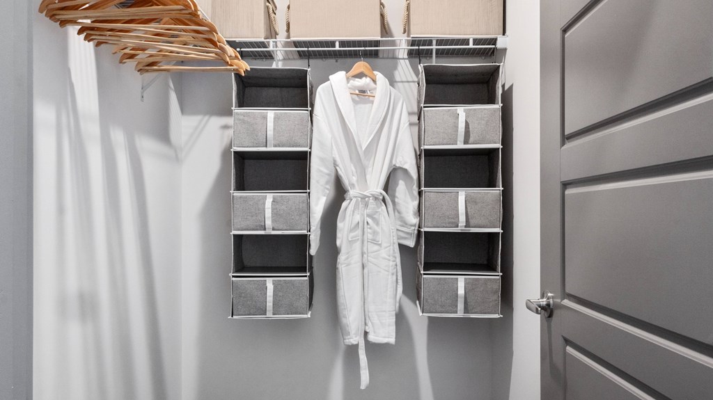 A white robe is hanging on a rack in a room.