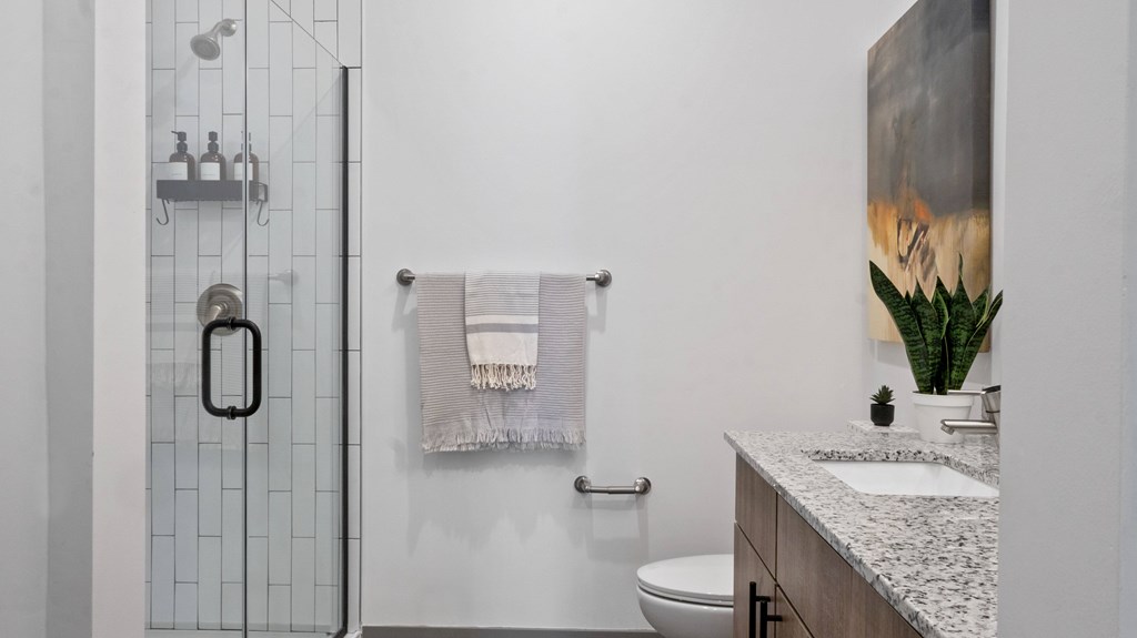 A bathroom with a toilet, sink, and a shower with a glass door.