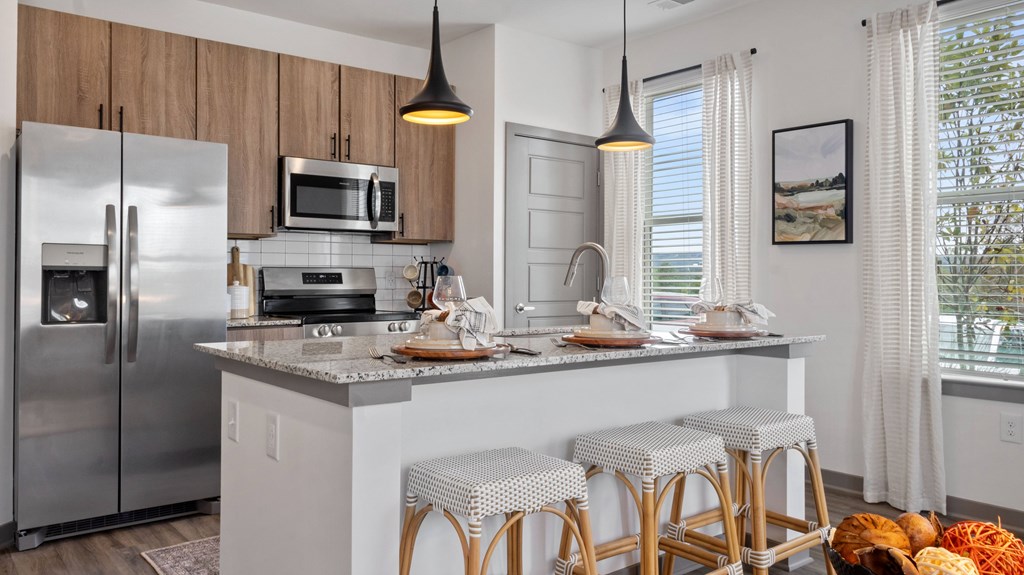 A modern kitchen with a refrigerator, microwave, and stove top oven.